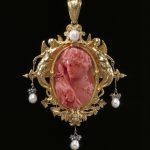 Pendant with a coral cameo depicting Bacchus, the sculpted gold frame decorated with winged mermaids and hung with pearls and diamond sparks.