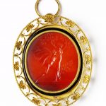 Vertical oval intaglio. Red translucent carnelian. On the right a male figure, probably Apollo, naked except for a cloak, reaches left to clasp the figure of a naked female, probably Daphne