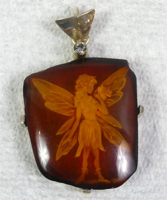 Intaglio cut amber fairy pendant with silver mount and center diamond